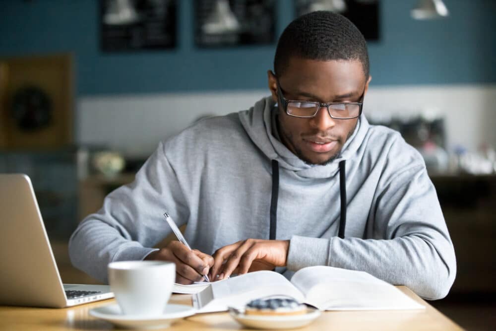 focused,millennial,african,american,student,in,glasses,making,notes,writing
